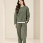 Woman wearing an olive green crew-neck sweatshirt with side-zip details and matching wide-leg trousers