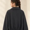 Woman wearing a black cropped double-breasted jacket with oversized lapels and four front buttons