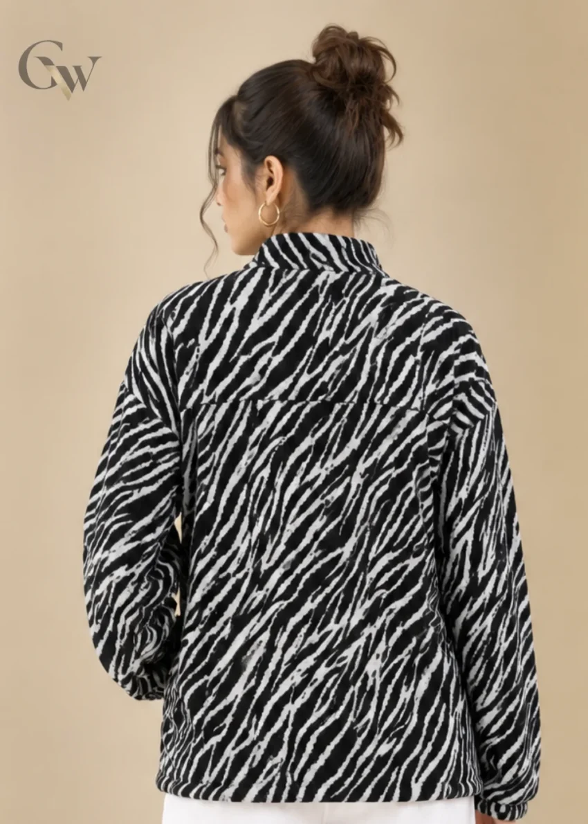 Woman wearing a black and white zebra print zip-up jacket with long sleeves and side pockets.