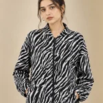 Woman wearing a black and white zebra print zip-up jacket with long sleeves and side pockets.