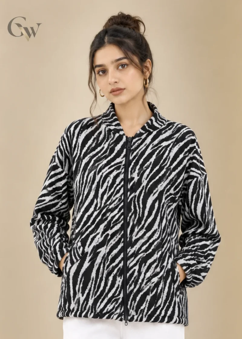 Woman wearing a black and white zebra print zip-up jacket with long sleeves and side pockets.