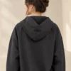 Woman wearing a charcoal zip-up hooded jacket with long sleeves and front pockets