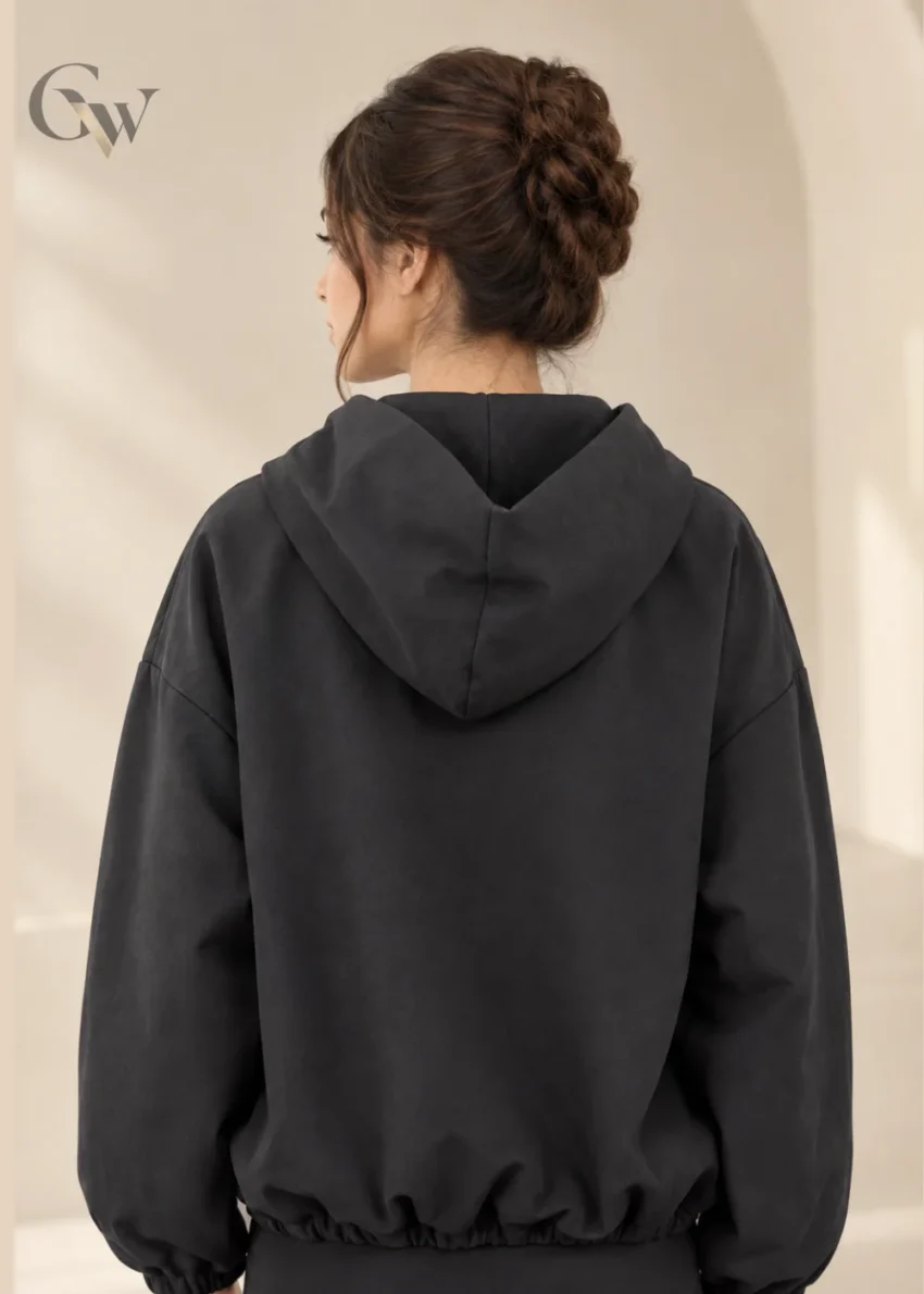 Woman wearing a charcoal zip-up hooded jacket with long sleeves and front pockets