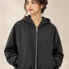 Woman wearing a charcoal zip-up hooded jacket with long sleeves and front pockets