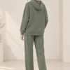 Woman wearing an olive green hooded co-ord set with white drawstrings and flap-detail pockets.