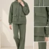 Woman wearing an olive green hooded co-ord set with white drawstrings and flap-detail pockets.